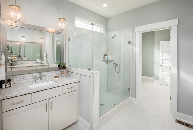 bathroom with tile floors, a shower with door, and vanity