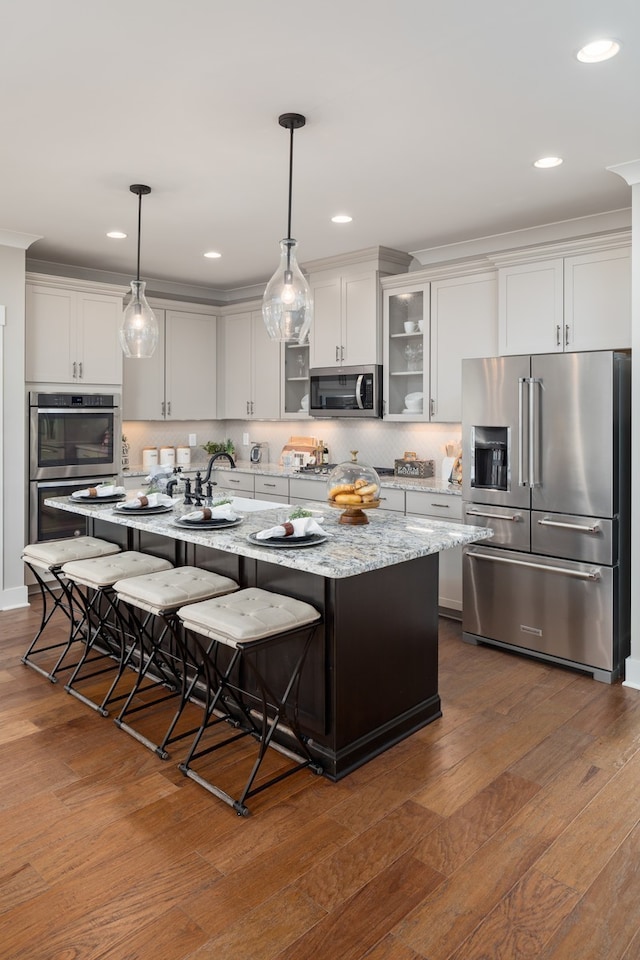 kitchen with dark hardwood / wood-style floors, a kitchen breakfast bar, hanging light fixtures, appliances with stainless steel finishes, and a center island