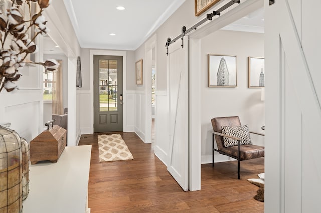 entryway featuring a barn door, ornamental molding, and dark hardwood / wood-style floors