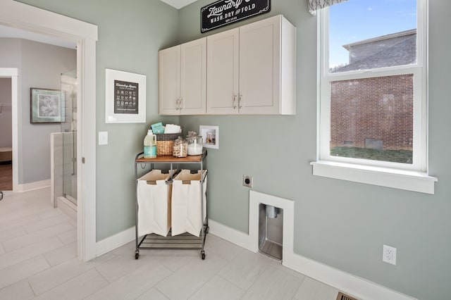 laundry room with hookup for an electric dryer, cabinets, and light tile floors