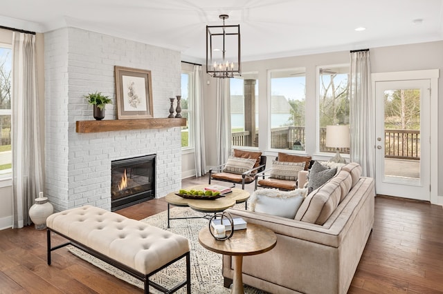 interior space with an inviting chandelier, dark hardwood / wood-style flooring, a fireplace, and ornamental molding