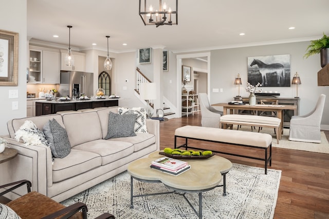 living room with crown molding, light wood-type flooring, and an inviting chandelier