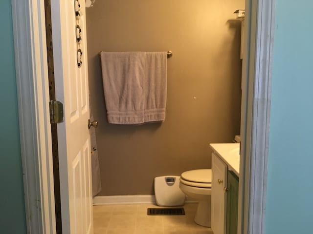 bathroom with toilet, vanity, and tile flooring