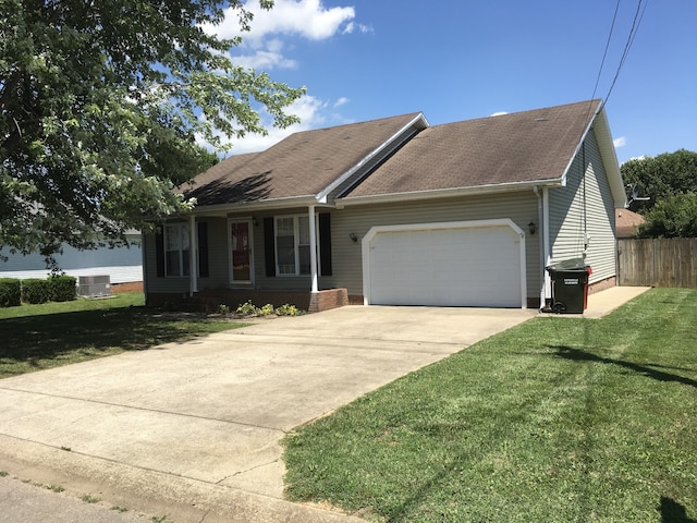 view of front of home featuring a front yard, central AC, and a garage