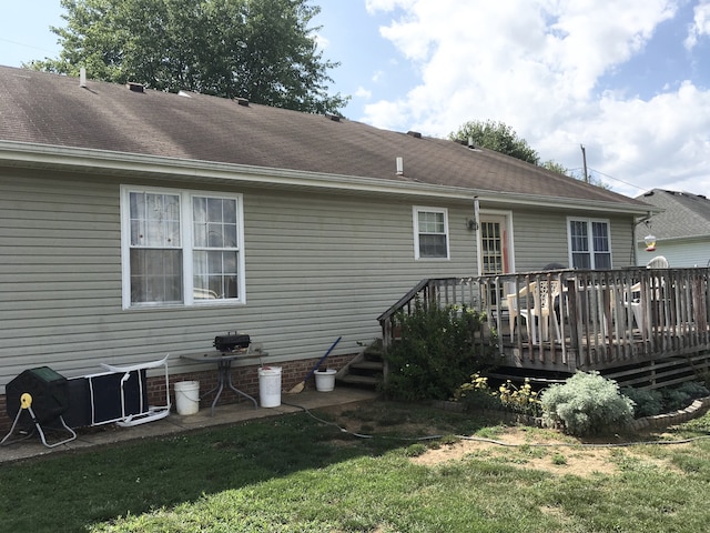 back of property featuring a wooden deck and a lawn