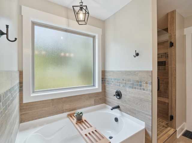 bathroom with tile walls and separate shower and tub