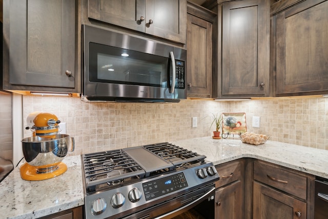 kitchen featuring backsplash, range with gas stovetop, dark brown cabinets, and light stone counters