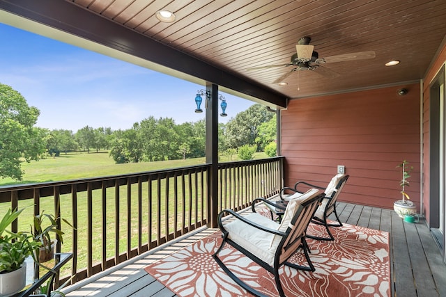 wooden terrace with ceiling fan and a yard