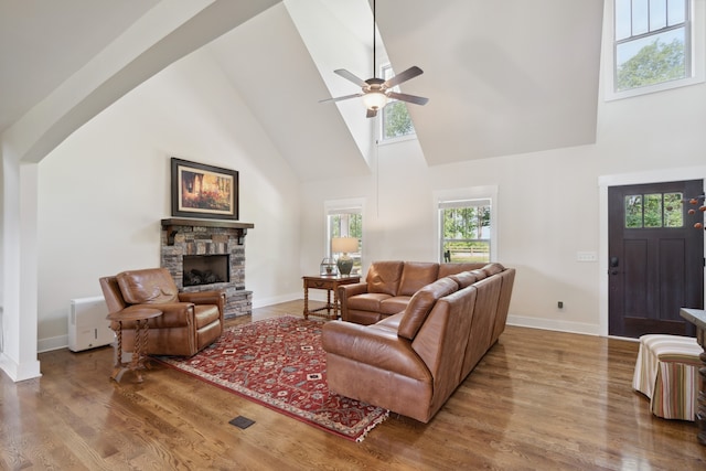 living room with ceiling fan, high vaulted ceiling, dark wood-type flooring, and a fireplace