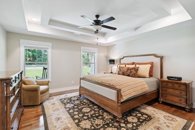 bedroom with a tray ceiling, ceiling fan, and dark wood-type flooring