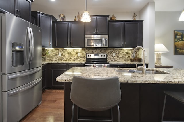 kitchen with tasteful backsplash, dark hardwood / wood-style floors, stainless steel appliances, sink, and hanging light fixtures