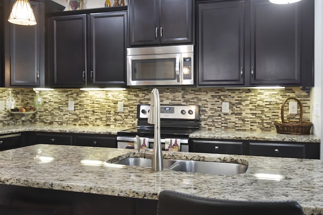 kitchen with tasteful backsplash, appliances with stainless steel finishes, and light stone counters