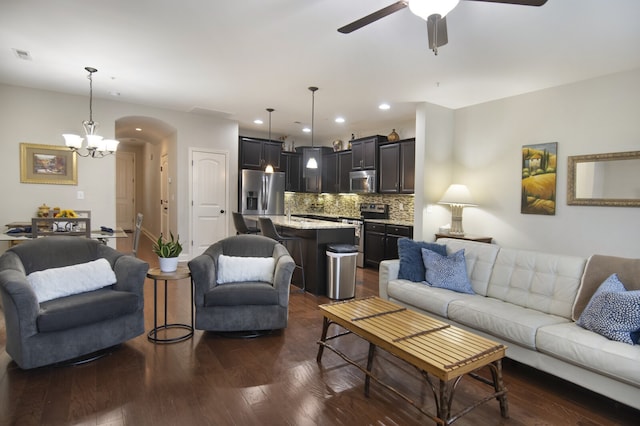 living room with dark hardwood / wood-style floors and ceiling fan with notable chandelier