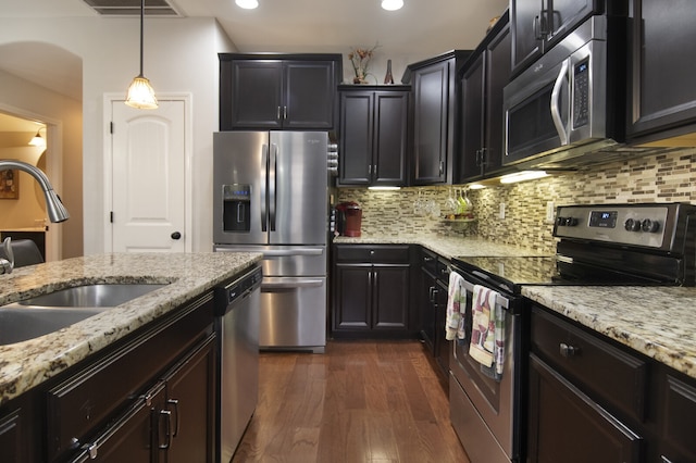 kitchen with appliances with stainless steel finishes, backsplash, dark hardwood / wood-style flooring, and decorative light fixtures