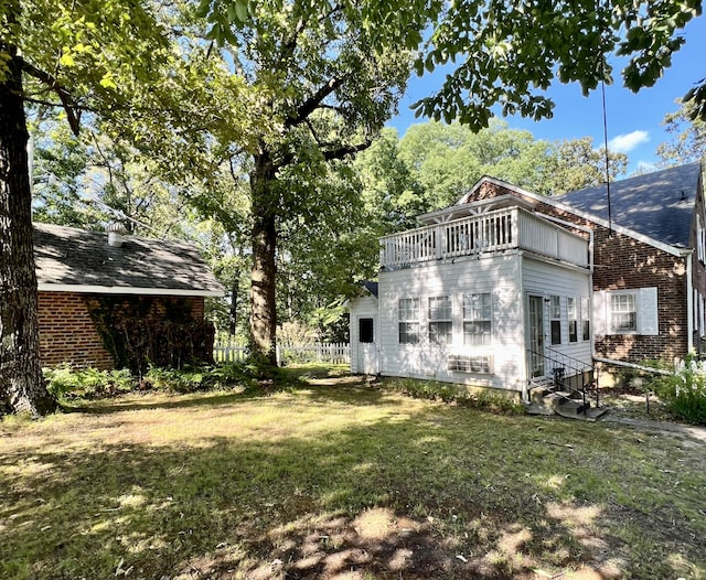 rear view of property with a balcony and a lawn