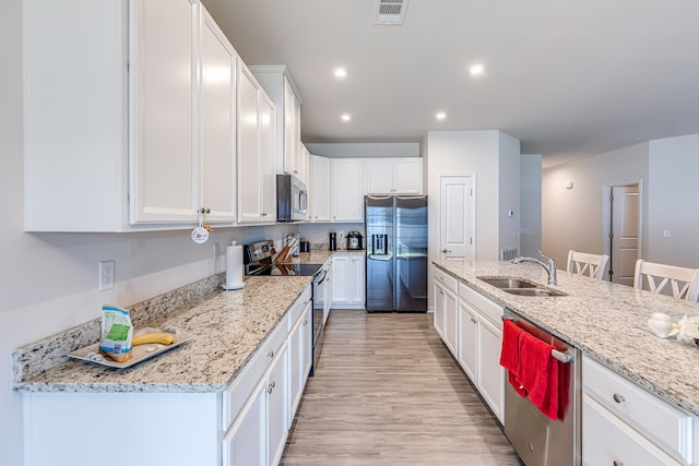 kitchen with light stone counters, stainless steel appliances, light wood-type flooring, and sink