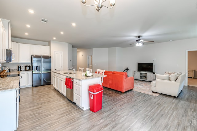 kitchen with sink, appliances with stainless steel finishes, ceiling fan with notable chandelier, white cabinetry, and light wood-type flooring