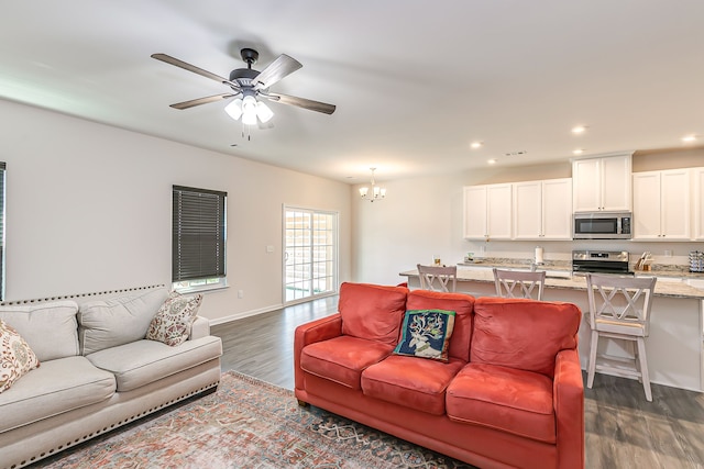 living room featuring dark wood-type flooring and ceiling fan with notable chandelier