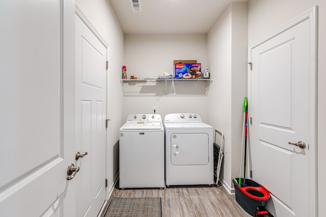 laundry room with light wood-type flooring and washer and clothes dryer