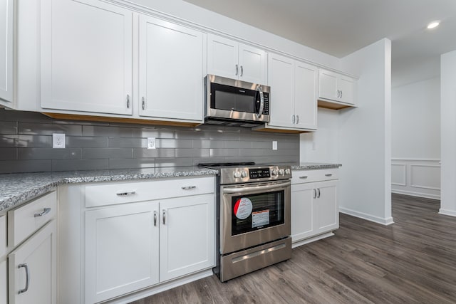 kitchen featuring light stone countertops, white cabinetry, dark wood-type flooring, appliances with stainless steel finishes, and tasteful backsplash