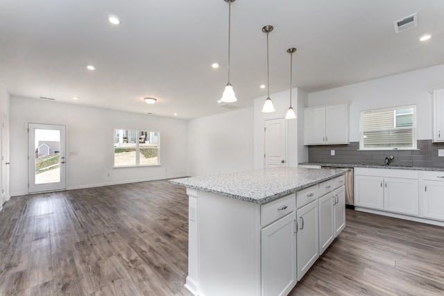 kitchen with hanging light fixtures, tasteful backsplash, a kitchen island, wood-type flooring, and white cabinets