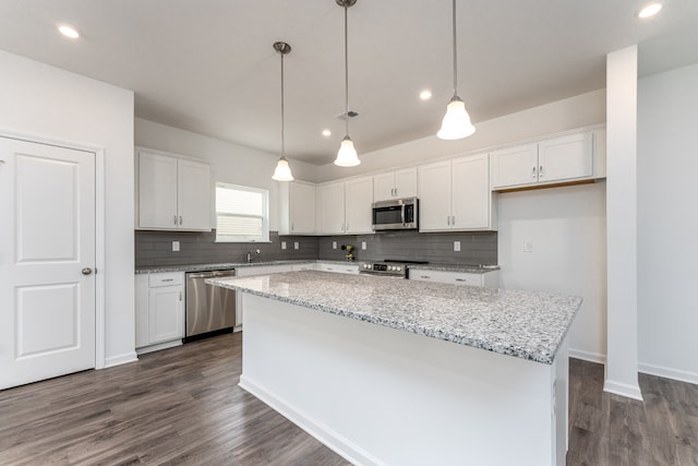 kitchen featuring white cabinetry, hanging light fixtures, dark wood-type flooring, appliances with stainless steel finishes, and a center island