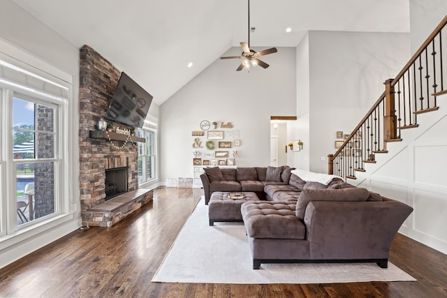 living room featuring ceiling fan, a stone fireplace, and dark hardwood / wood-style floors