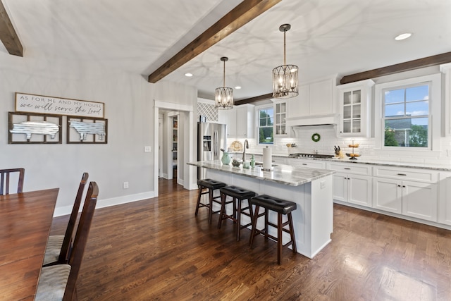 kitchen featuring white cabinets, dark hardwood / wood-style floors, light stone counters, and a kitchen island with sink