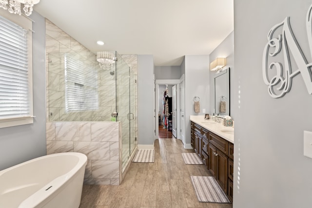 bathroom with double sink vanity, a chandelier, wood-type flooring, and separate shower and tub