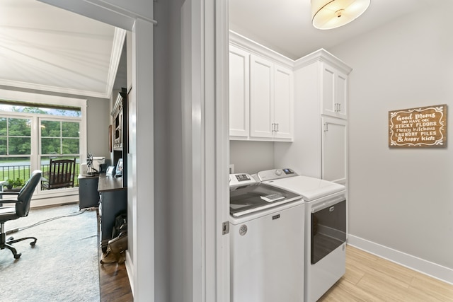 clothes washing area featuring cabinets, light hardwood / wood-style flooring, washing machine and clothes dryer, and ornamental molding