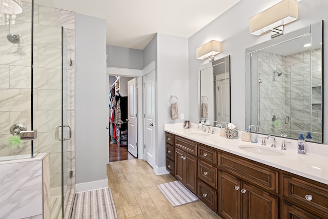 bathroom featuring double sink, a shower with door, vanity with extensive cabinet space, and hardwood / wood-style floors