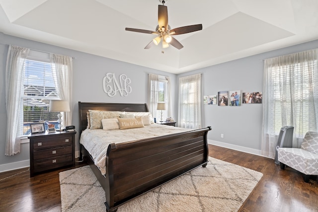 bedroom with a tray ceiling, ceiling fan, and dark hardwood / wood-style floors