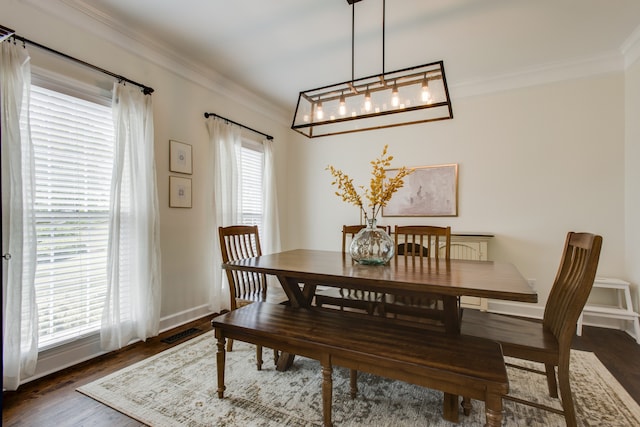 dining space with ornamental molding, dark wood-type flooring, an inviting chandelier, and a wealth of natural light