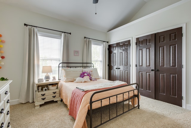 bedroom featuring lofted ceiling, two closets, light carpet, and multiple windows