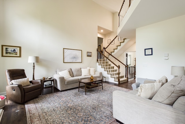 living room with dark wood-type flooring and a towering ceiling