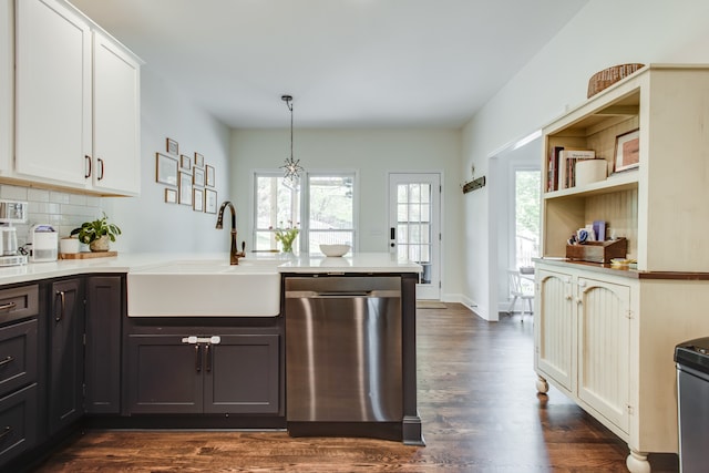 kitchen featuring dark wood-type flooring, white cabinets, sink, dishwasher, and hanging light fixtures