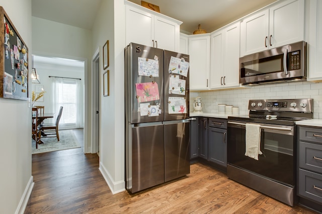 kitchen with white cabinets, stainless steel appliances, gray cabinetry, light hardwood / wood-style flooring, and backsplash