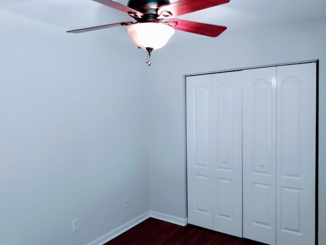 unfurnished bedroom featuring dark hardwood / wood-style floors, a closet, and ceiling fan