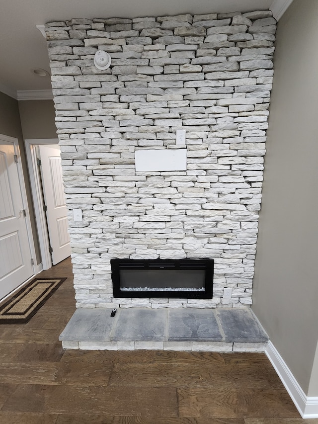 details with hardwood / wood-style floors, a stone fireplace, and crown molding