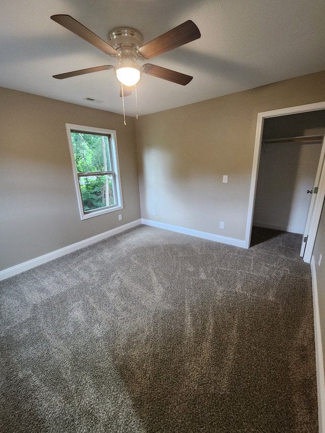 unfurnished bedroom with ceiling fan, a closet, and dark colored carpet