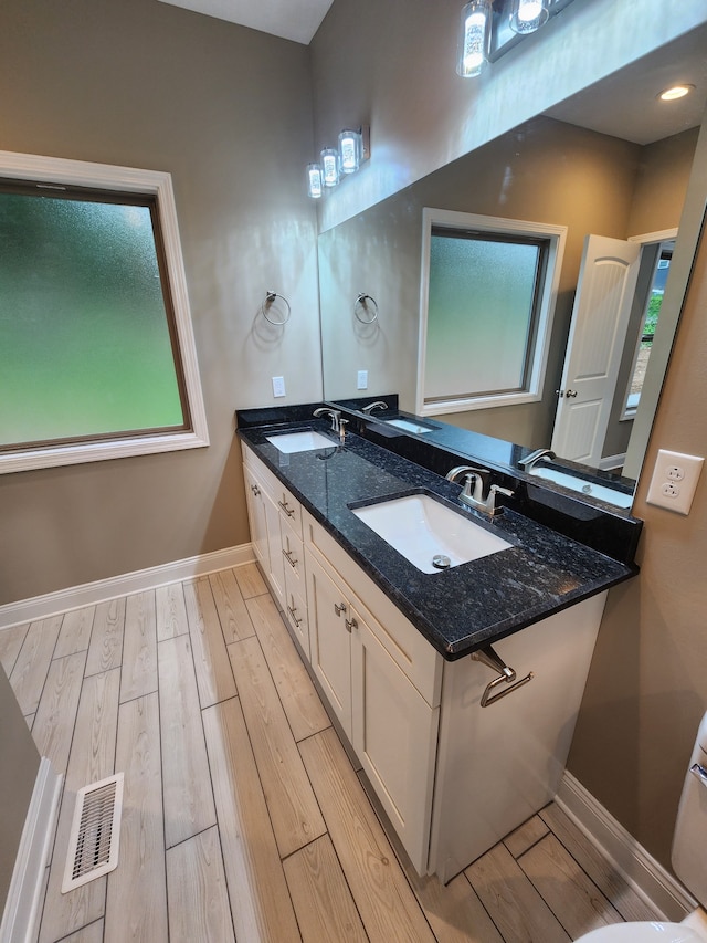 bathroom with double sink, oversized vanity, and hardwood / wood-style flooring