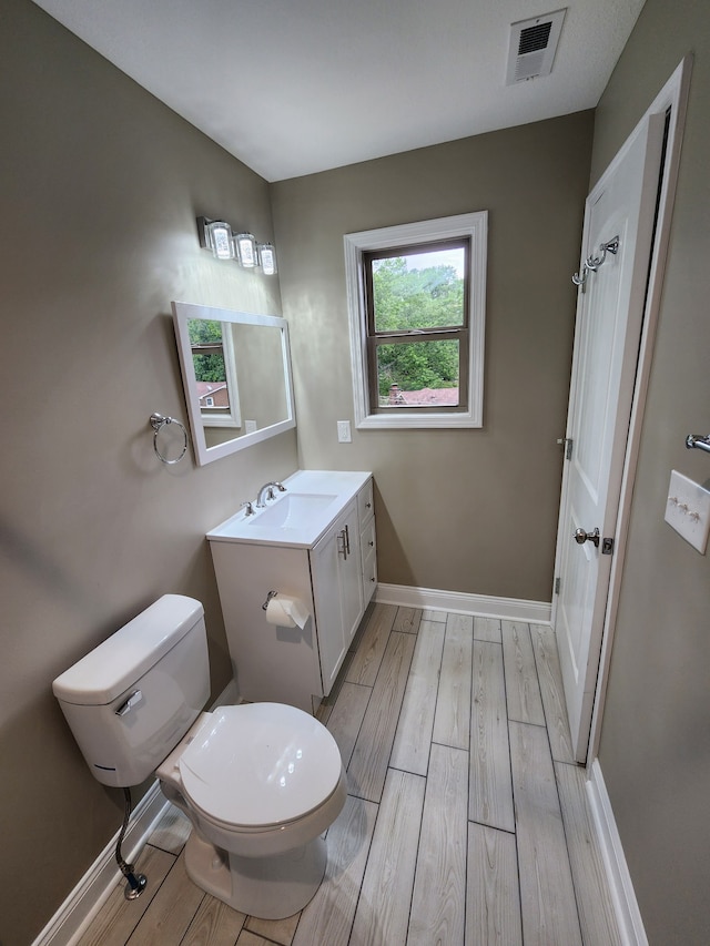 bathroom with hardwood / wood-style flooring, toilet, and vanity