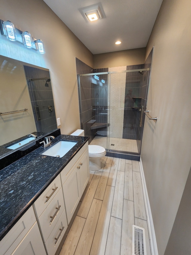 bathroom featuring an enclosed shower, toilet, hardwood / wood-style flooring, and vanity