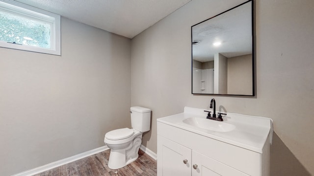 bathroom with hardwood / wood-style flooring, vanity with extensive cabinet space, and toilet