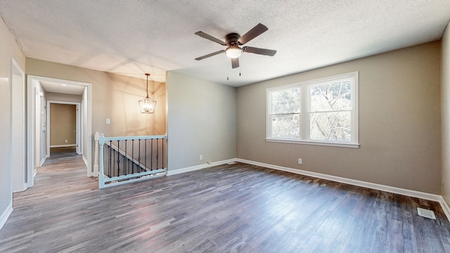 spare room with dark hardwood / wood-style flooring, a textured ceiling, and ceiling fan with notable chandelier