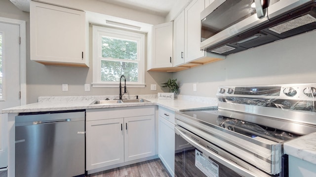 kitchen featuring appliances with stainless steel finishes, sink, light wood-type flooring, and white cabinetry