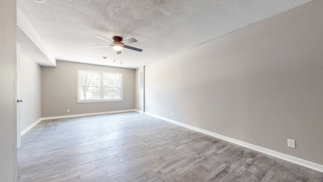 empty room with ceiling fan, a textured ceiling, and dark hardwood / wood-style flooring