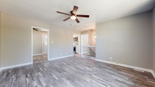 empty room with ceiling fan, a textured ceiling, and dark wood-type flooring