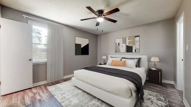 bedroom with a textured ceiling, dark hardwood / wood-style floors, and ceiling fan