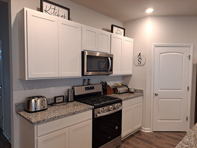 kitchen with gas stove, dark hardwood / wood-style floors, white cabinets, and light stone counters